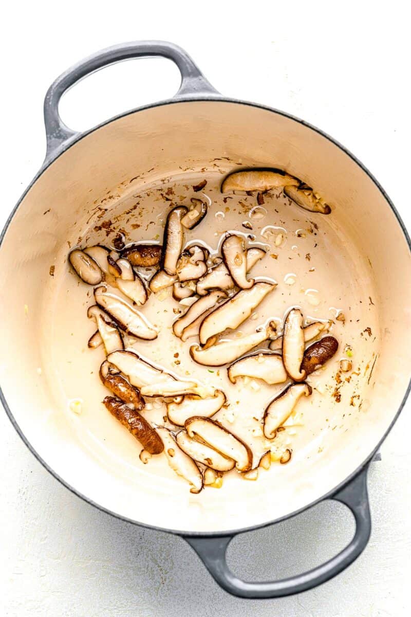 Sautéeing mushrooms and garlic in a soup pot.