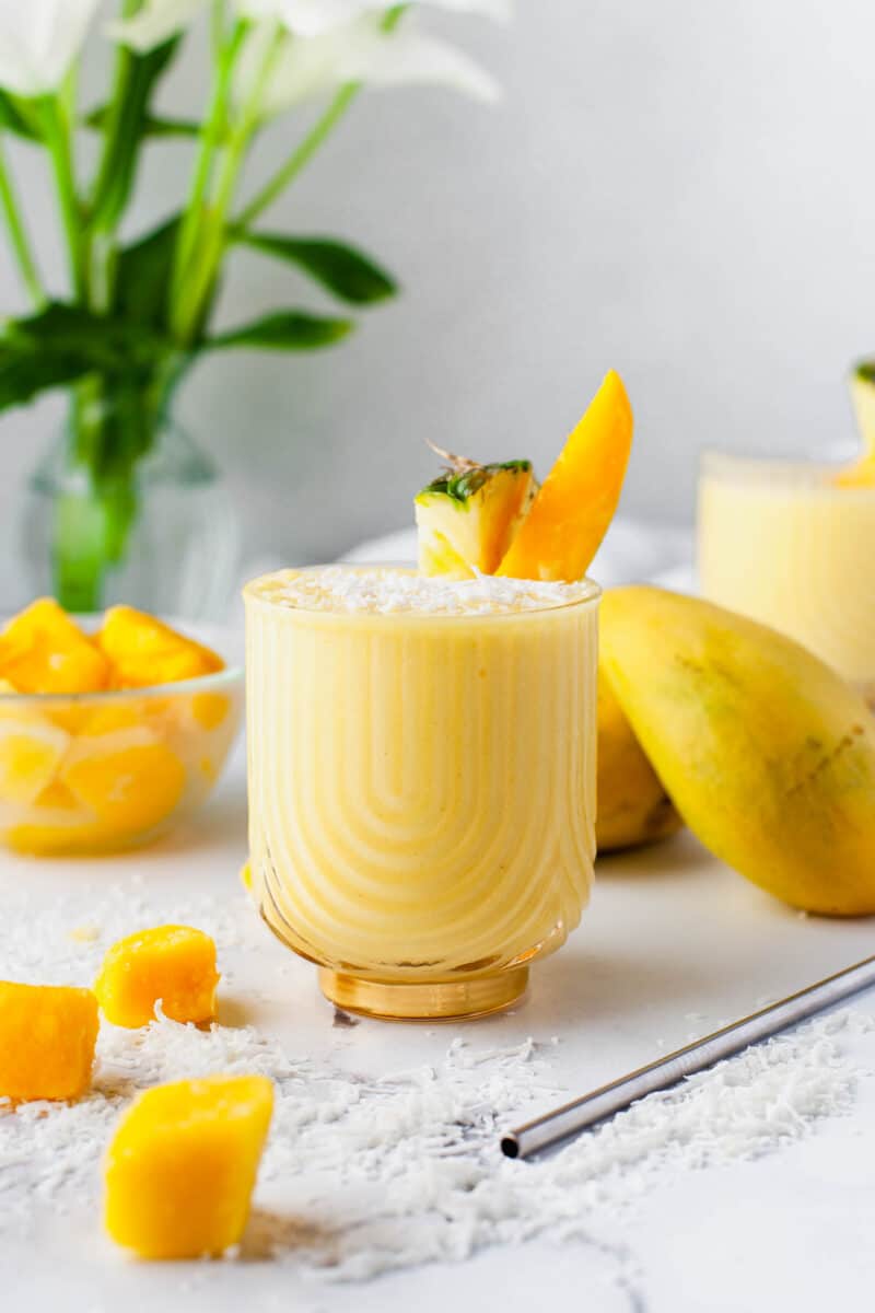 fruits are placed all around a glass of mango colada