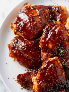 baked bbq chicken thighs with bbq sauce on a white plate