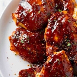 baked bbq chicken thighs with bbq sauce on a white plate