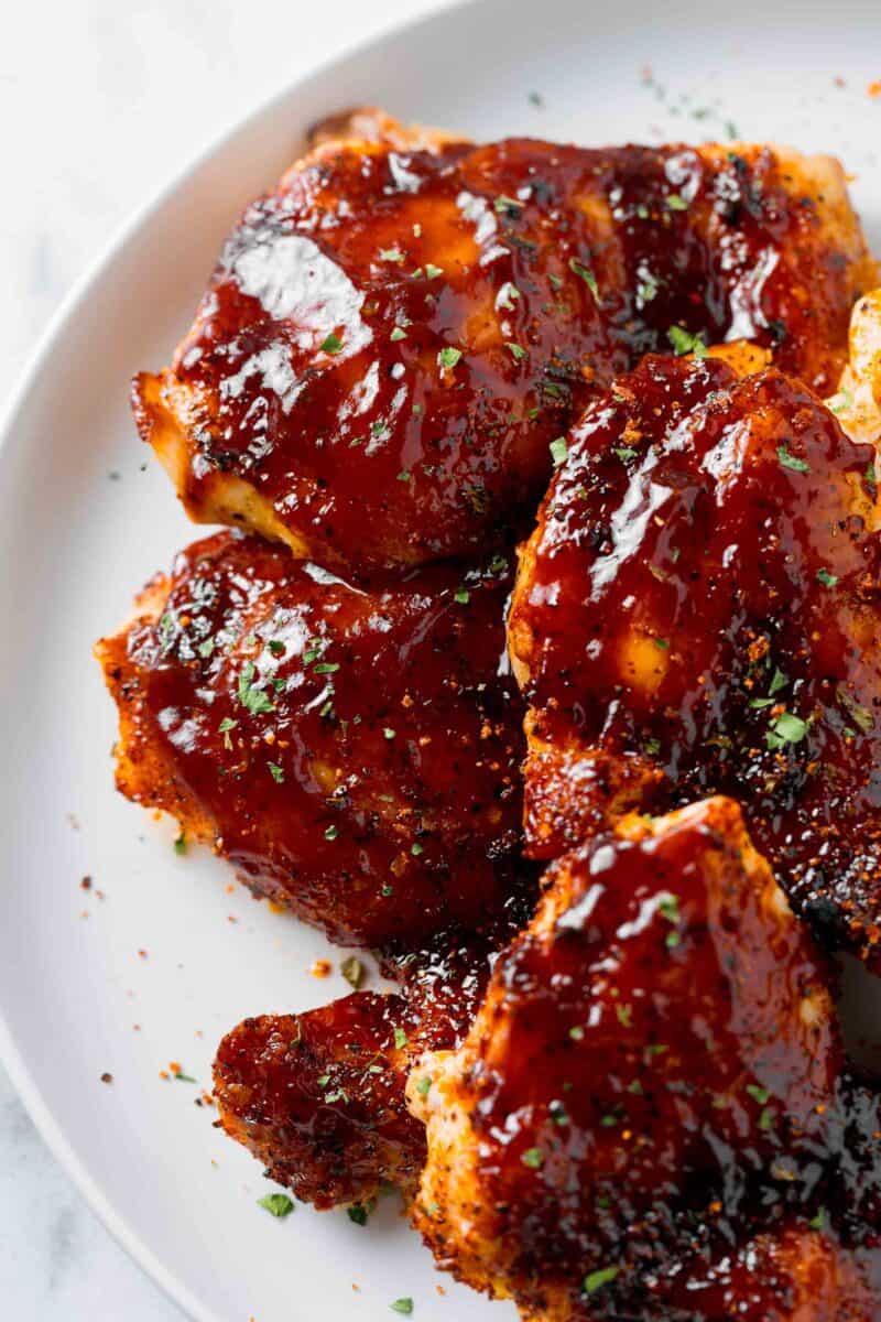 baked bbq chicken thighs with bbq sauce on a white plate
