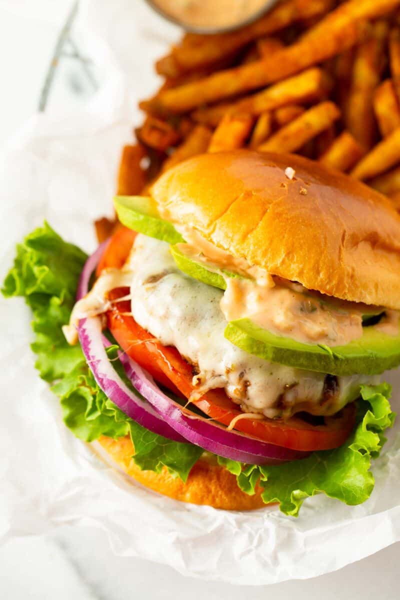 california burger on white parchment paper next to fries