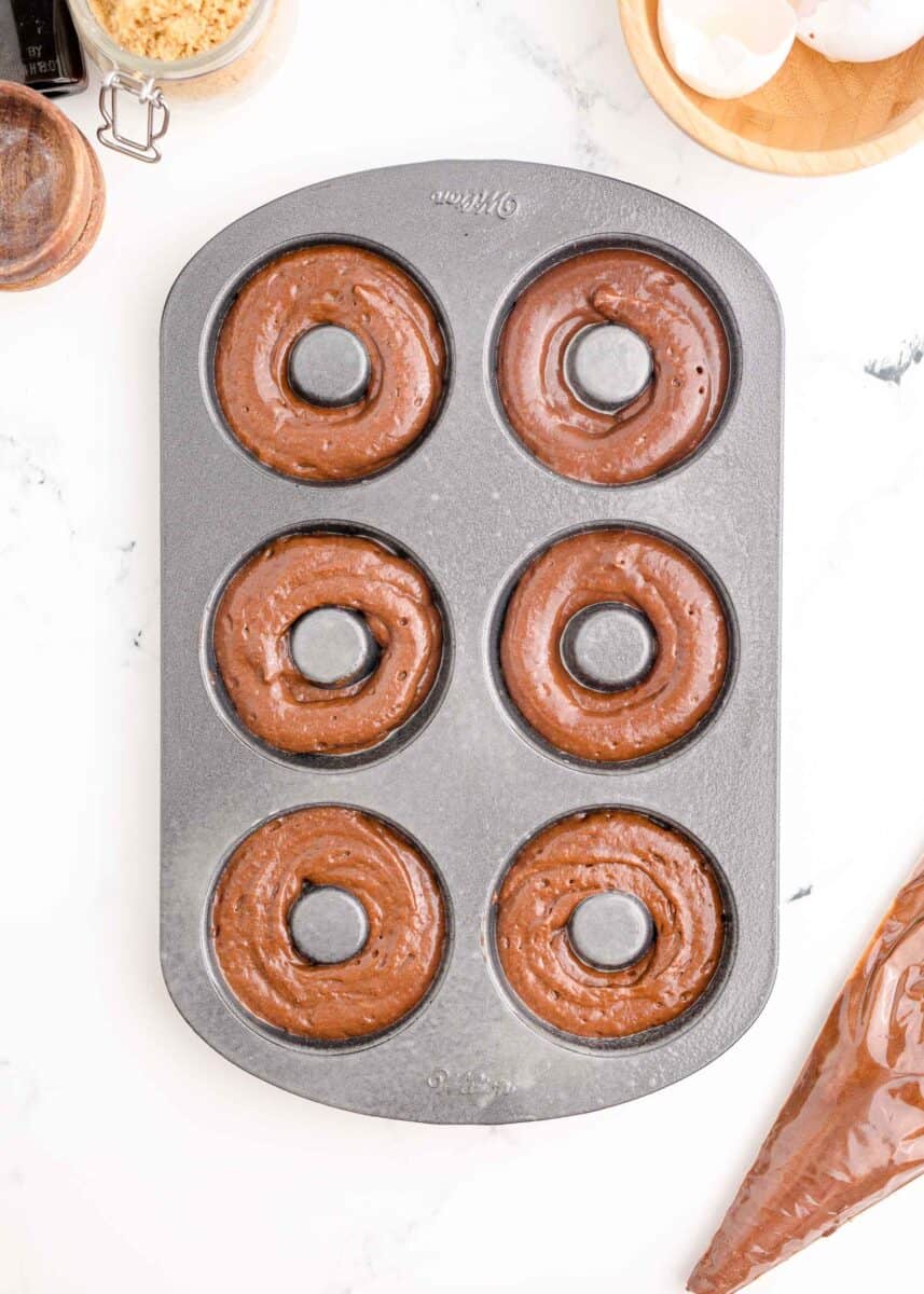 donut batter has been piped into a baking tin