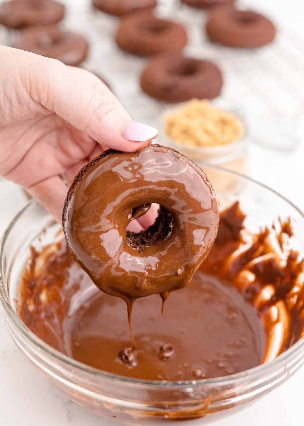 a donut is being dunked into chocolate frosting