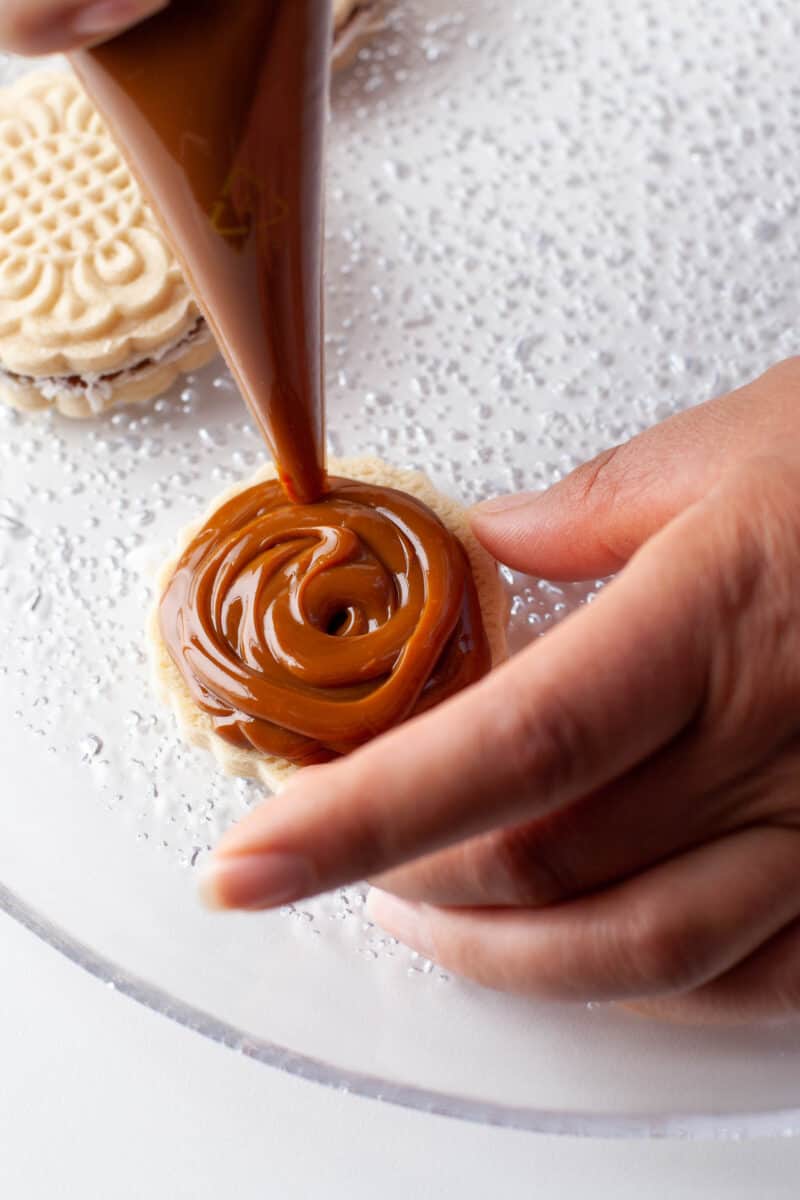 caramel is piped onto a cookie
