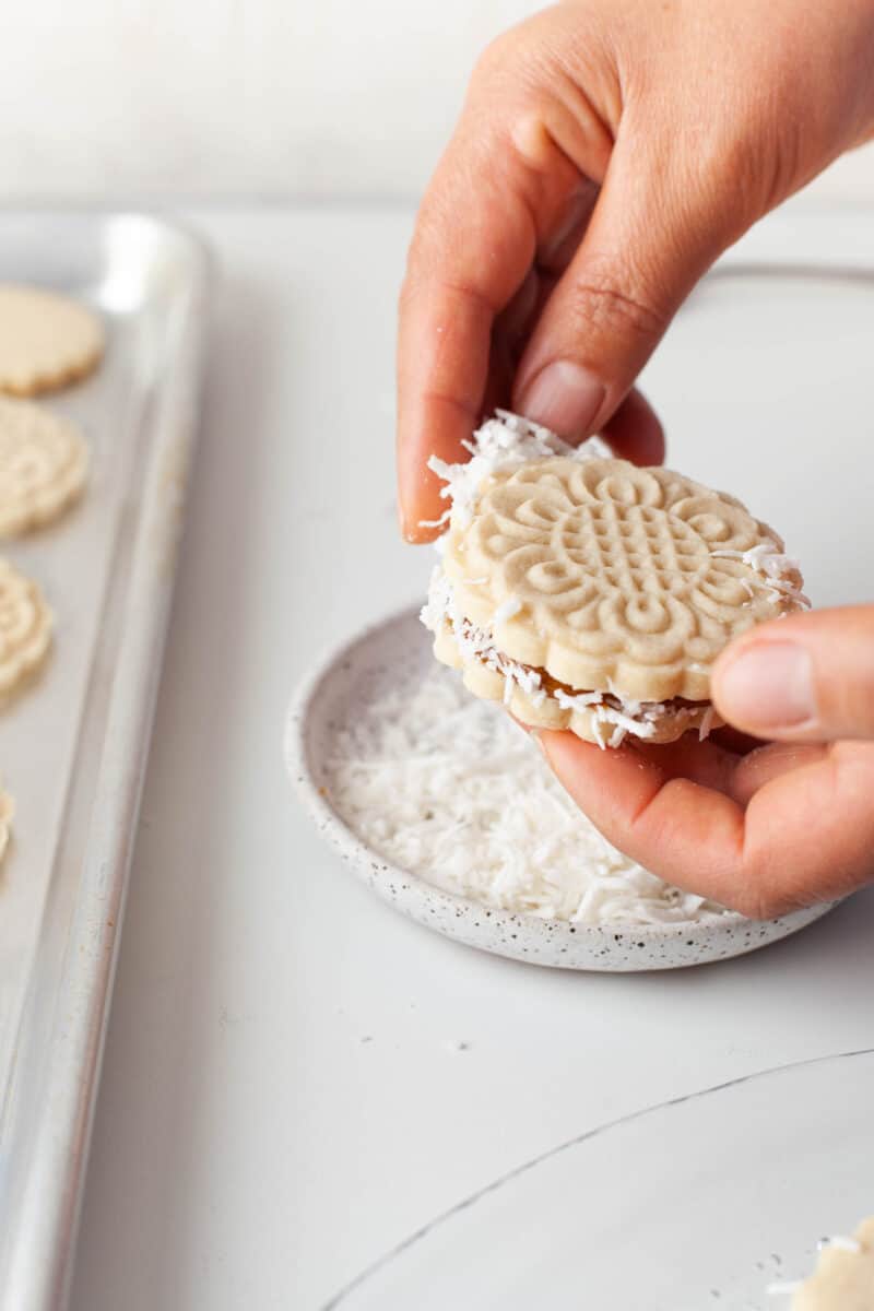 coconut flakes are being pressed around the edges of a dulce de leche cookie