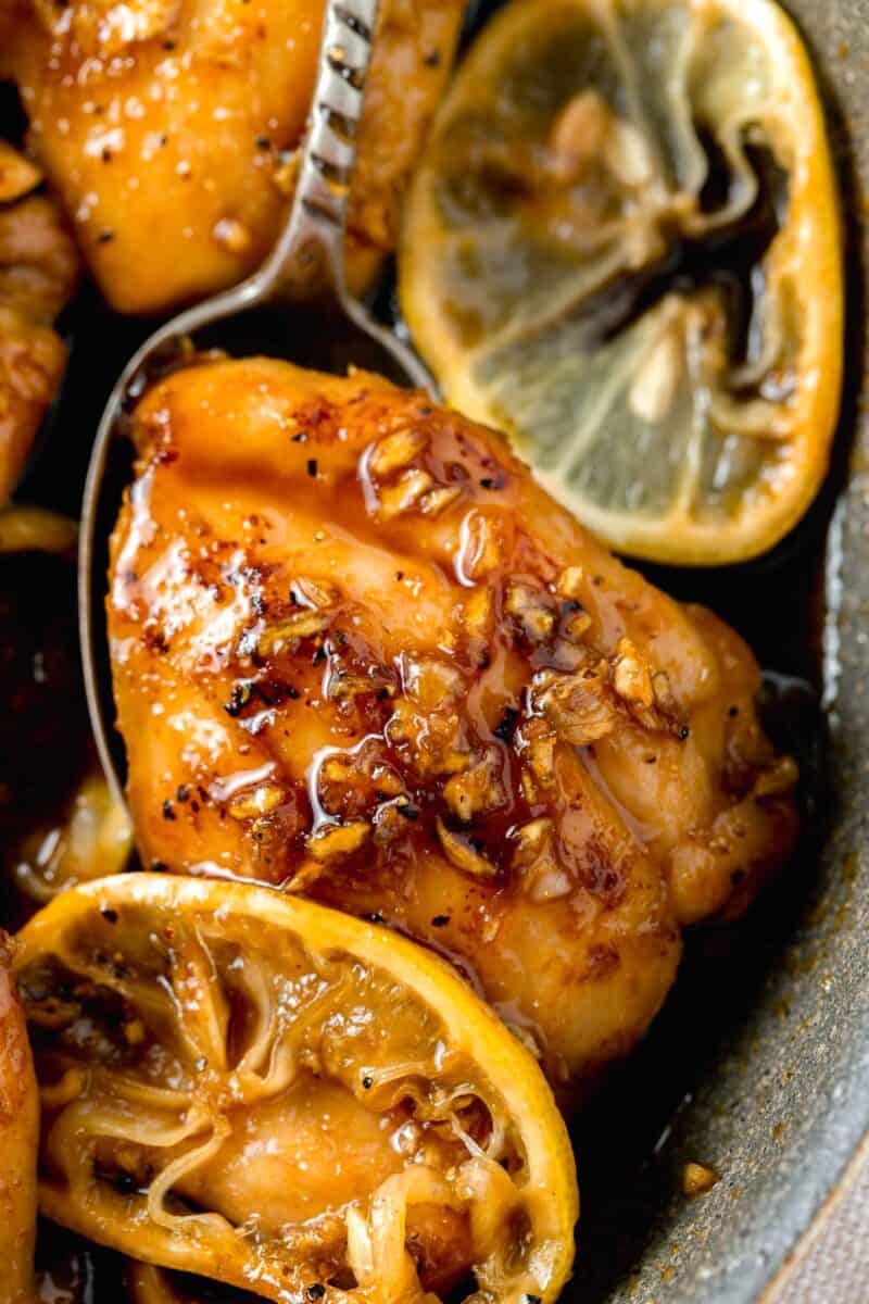 honey garlic lemon pepper chicken thigh under a metal spoon with minced garlic on top of the chicken thigh
