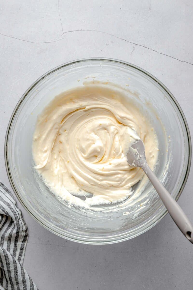 lemon cream cheese frosting in a clear bowl and grey spatula
