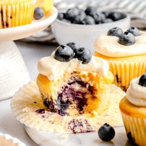the inside of a lemon blueberry cupcake after it has been bitten into. it shows the cupcake bursting with fresh blueberries