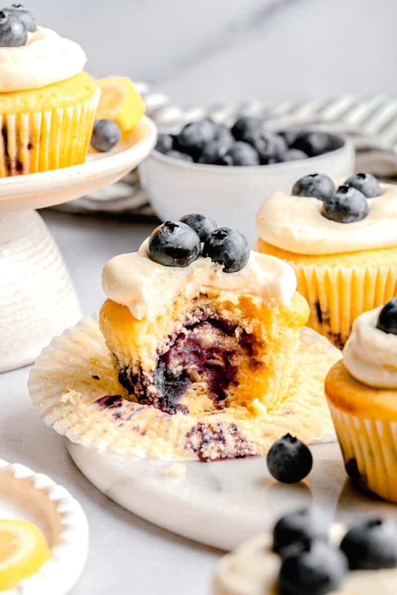 the inside of a lemon blueberry cupcake after it has been bitten into. it shows the cupcake bursting with fresh blueberries