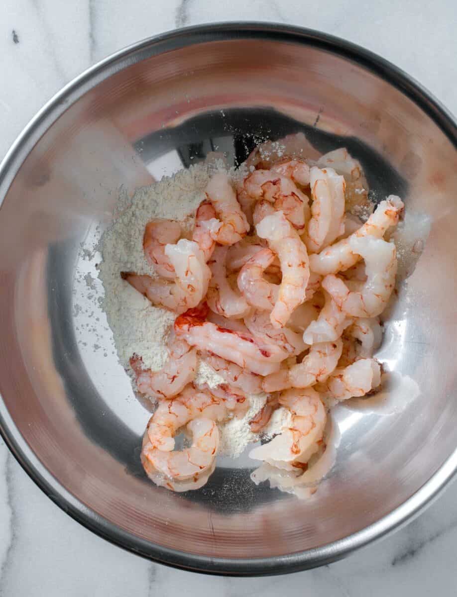 raw shrimp added to the metal bowl with the lemon pepper shrimp seasoning
