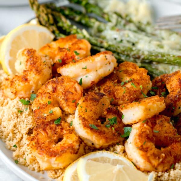 lemon pepper shrimp on a bed of couscous with fresh lemon slices and sprinkled fresh parsley on top