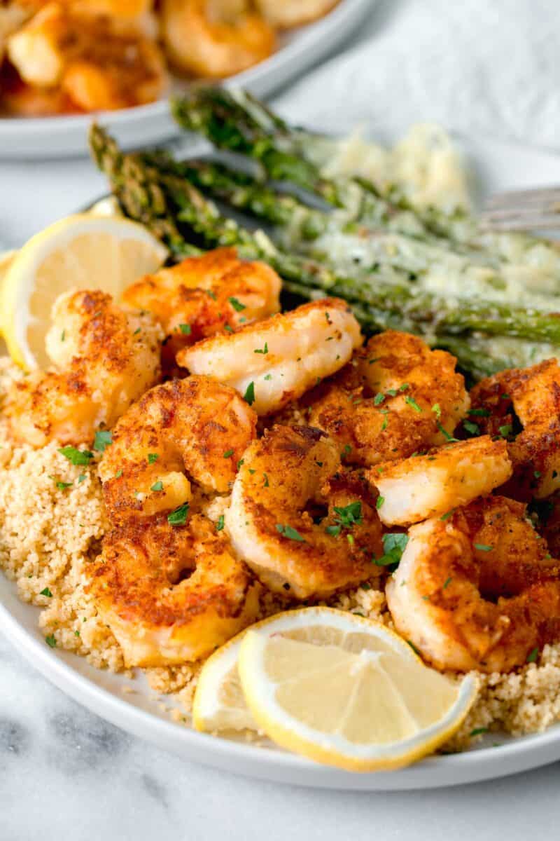 lemon pepper shrimp on a bed of couscous with fresh lemon slices and sprinkled fresh parsley on top