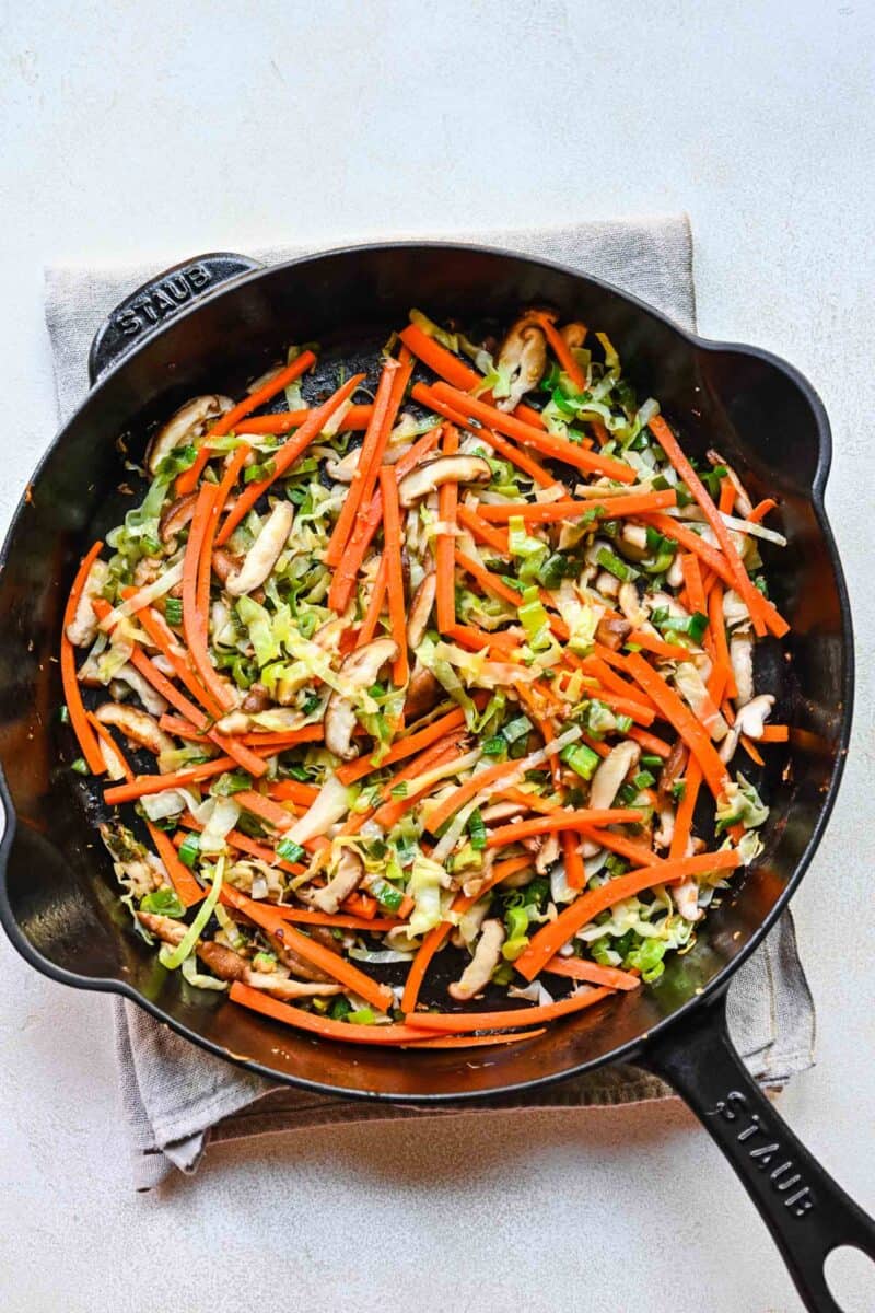 Sautéing sliced cabbage and julienned carrots.