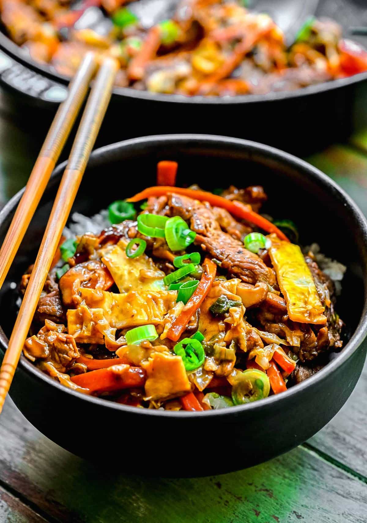 Moo shu pork served in bowls with chopsticks.