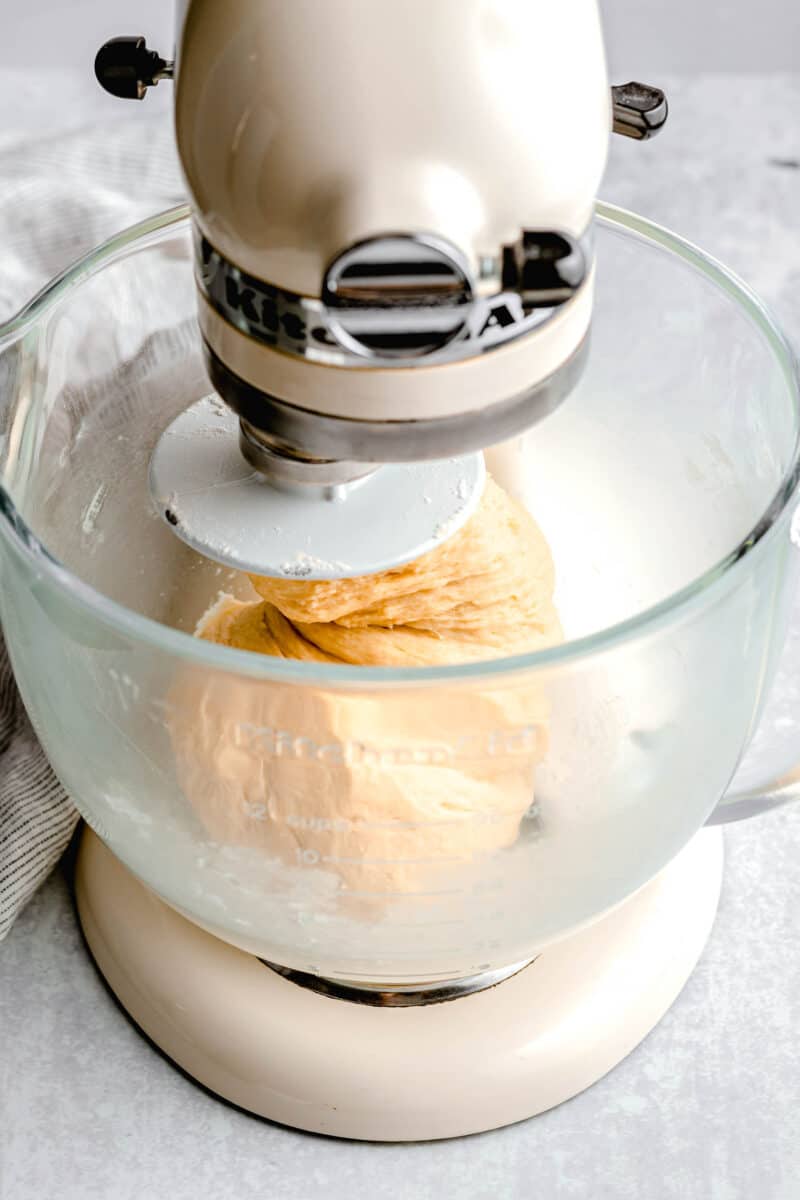 a white kitchenaid stand mixer with a glass bowl is kneading dough