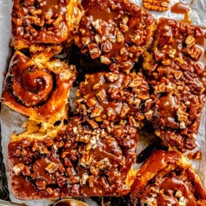 stick buns and caramel glaze on top of a metal baking sheet and parchment paper
