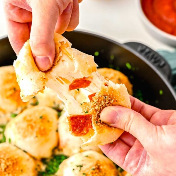 Pulling apart a pizza bite to reveal its cheesy insides.