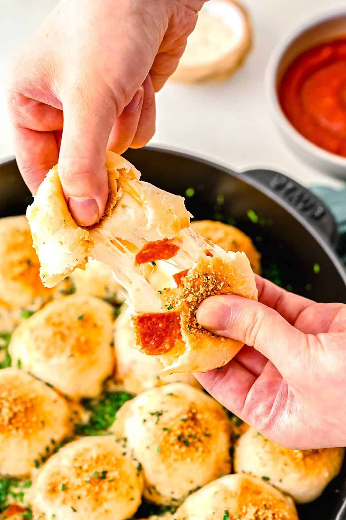 Pulling apart a pizza bite to reveal its cheesy insides.