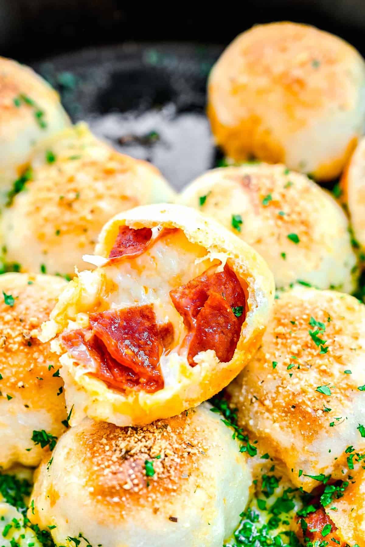 Pizza bites in a skillet. One has a bite taken out of it.