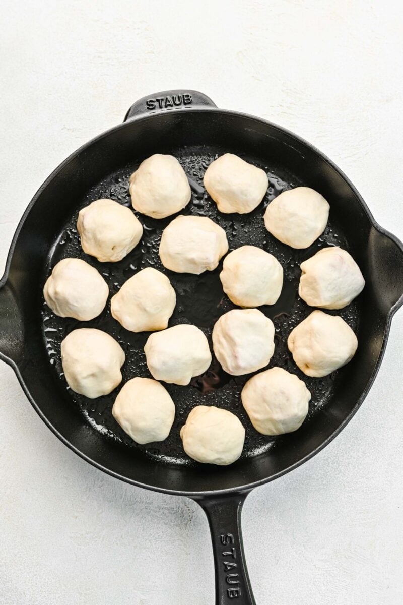 Pizza bites brushed in a skillet.