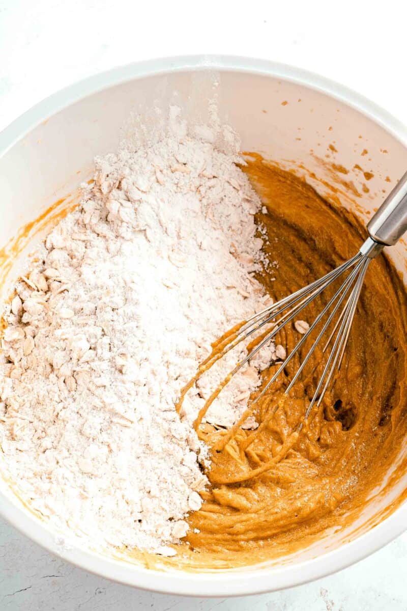 dry ingredients are being mixed with wet ingredients in a white bowl