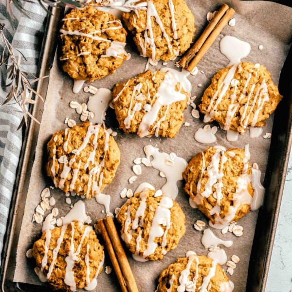 Overhead view of iced pumpkin oatmeal cookies on a baking sheet.
