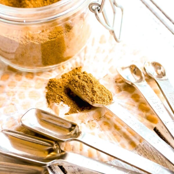 pumpkin pie spice in a measuring spoon next to a jar of pumpkin pie spice