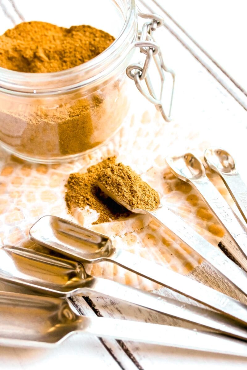 pumpkin pie spice in a measuring spoon next to a jar of pumpkin pie spice