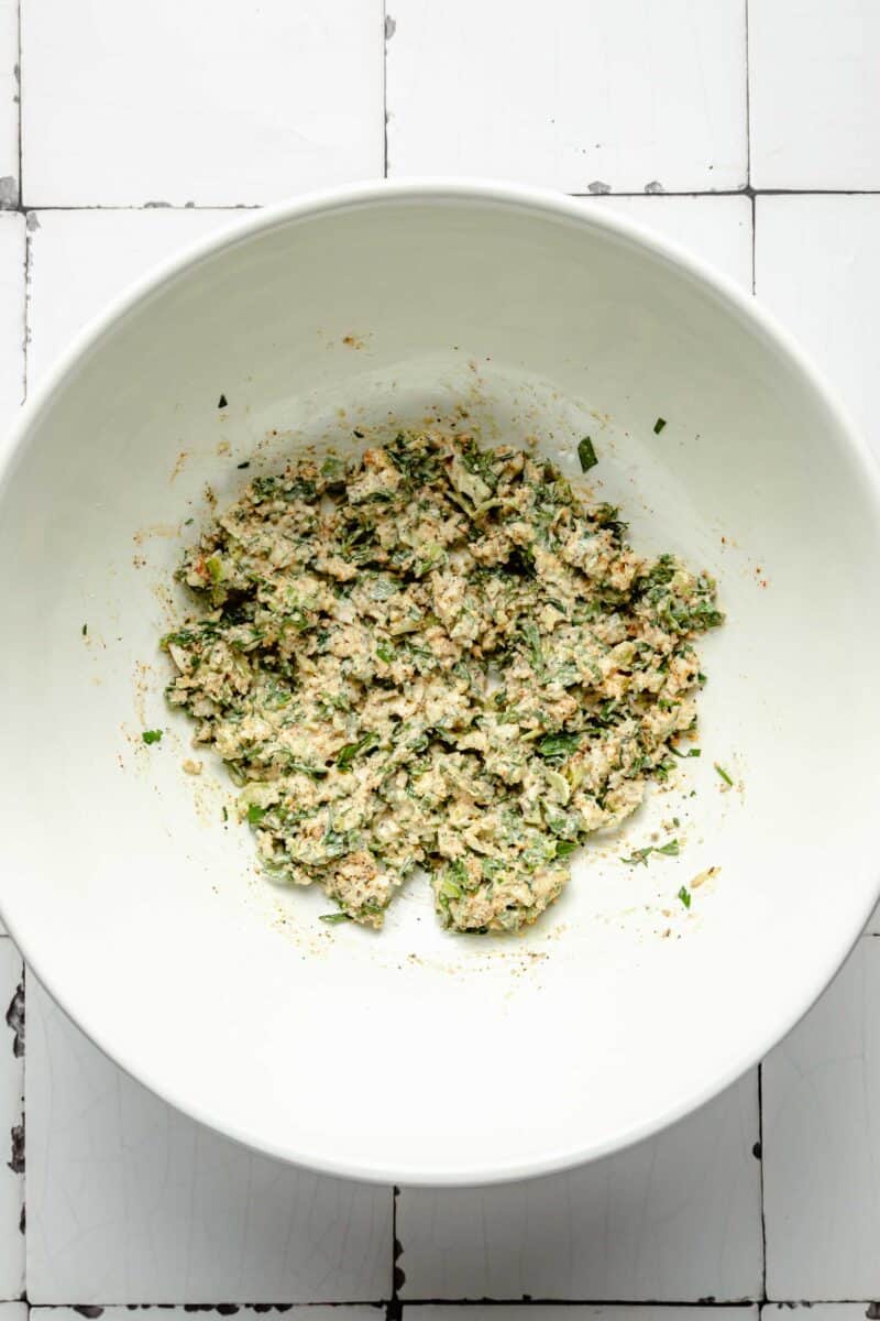 panko breadcrumbs are mixed with herbs and seasonings in a white bowl