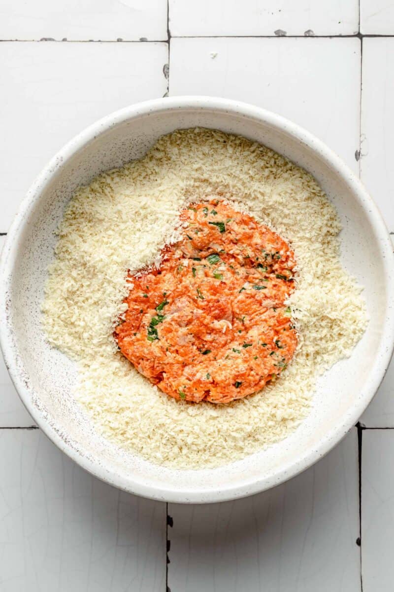 a salmon patty is being tossed in panko breadcrumbs