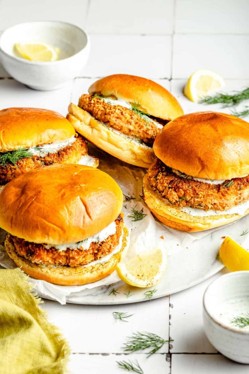 four salmon burgers are placed on a white plate