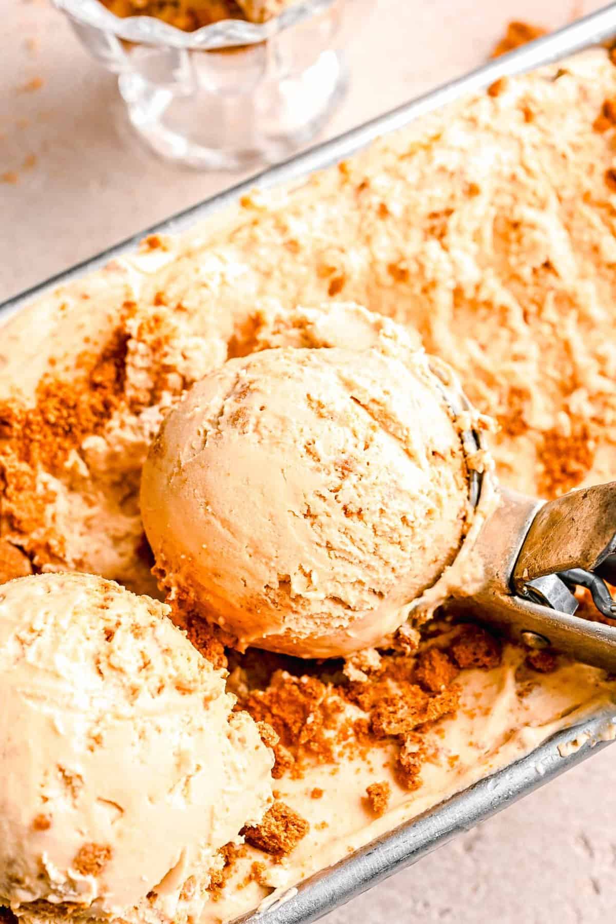 Scooping Biscoff ice cream out of a loaf pan.