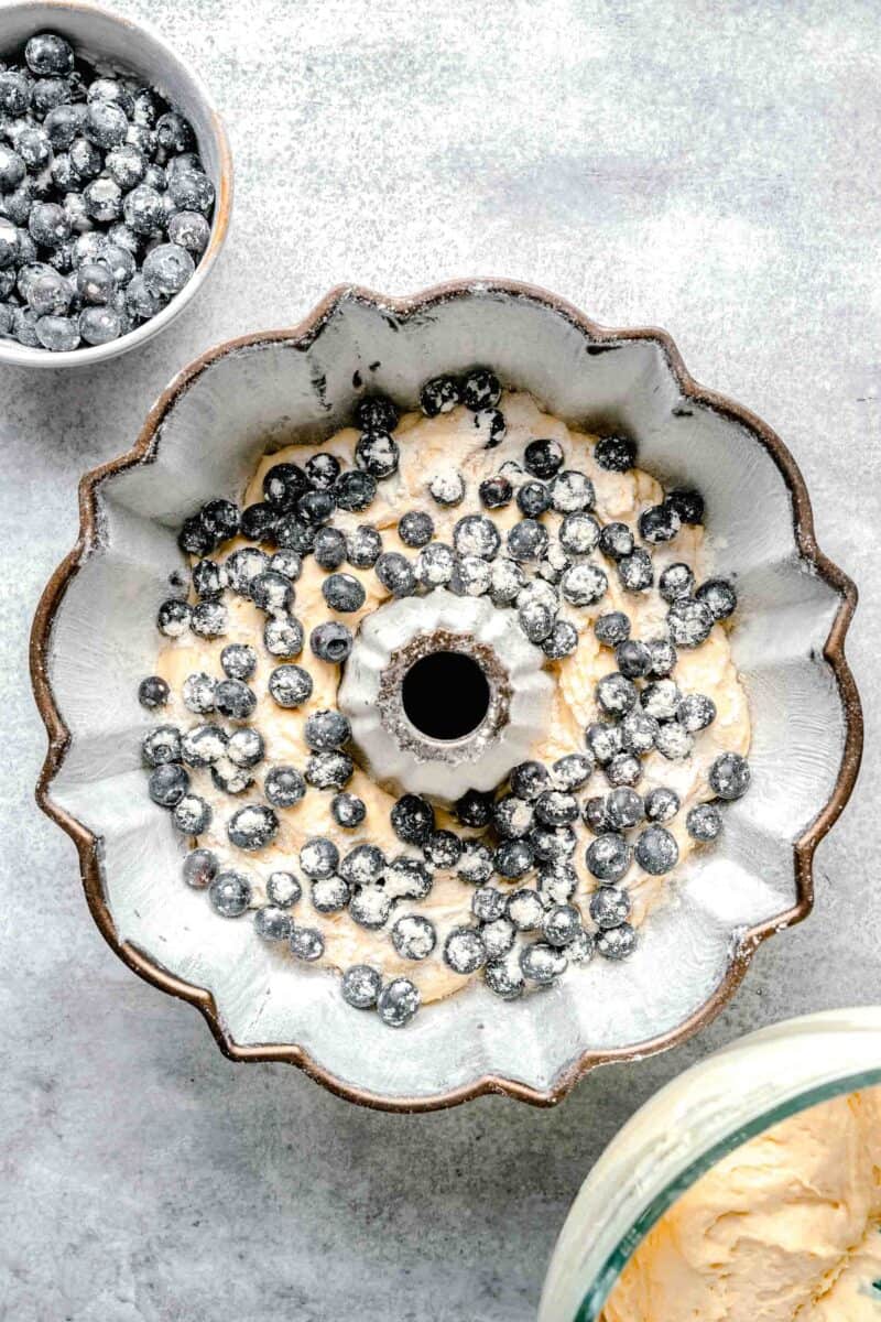 blueberries are placed on top of batter in a bundt pan