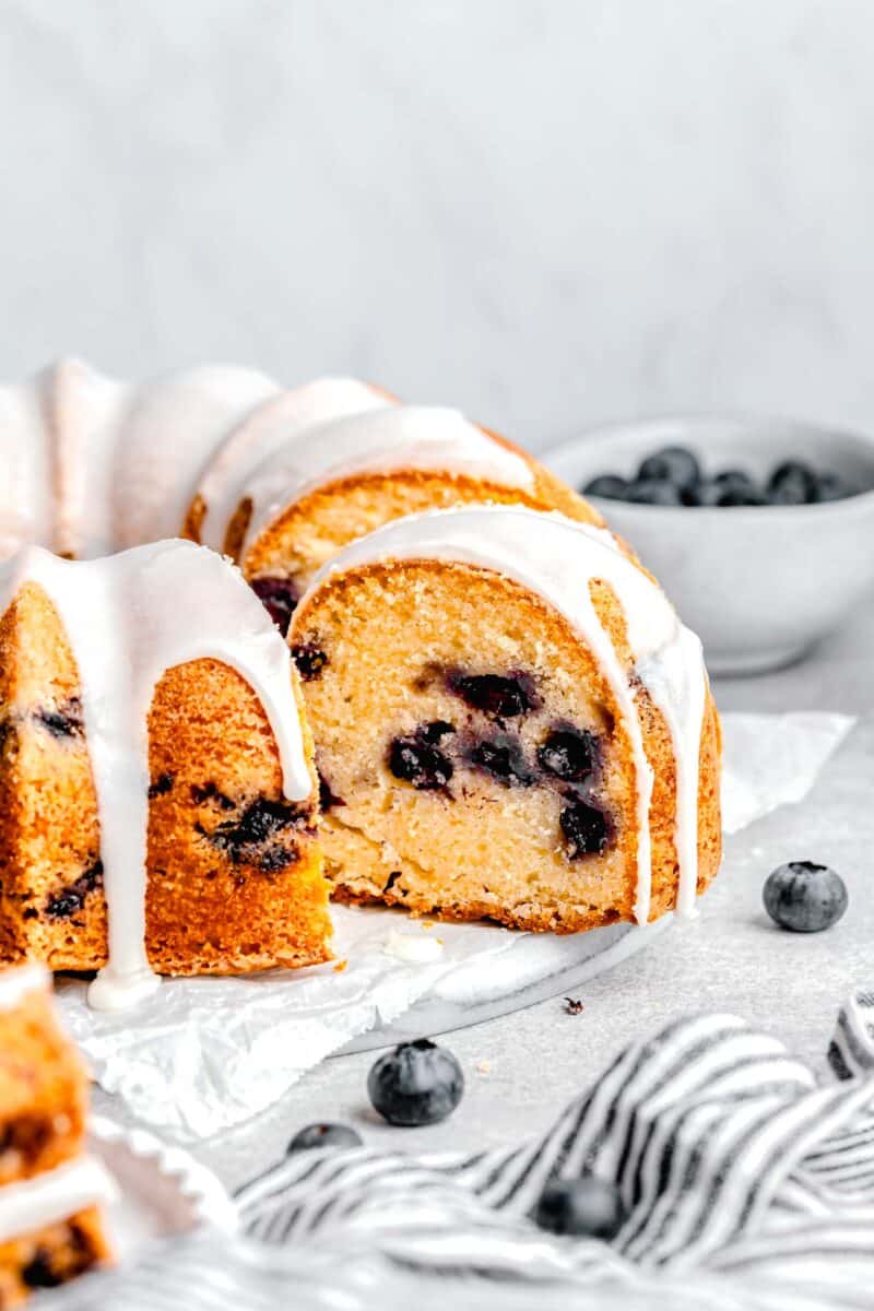 frosted bundt cake is placed next to a striped tea towel