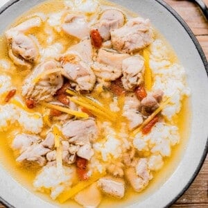 a bowl of chinese chicken soup with rice in a white bowl