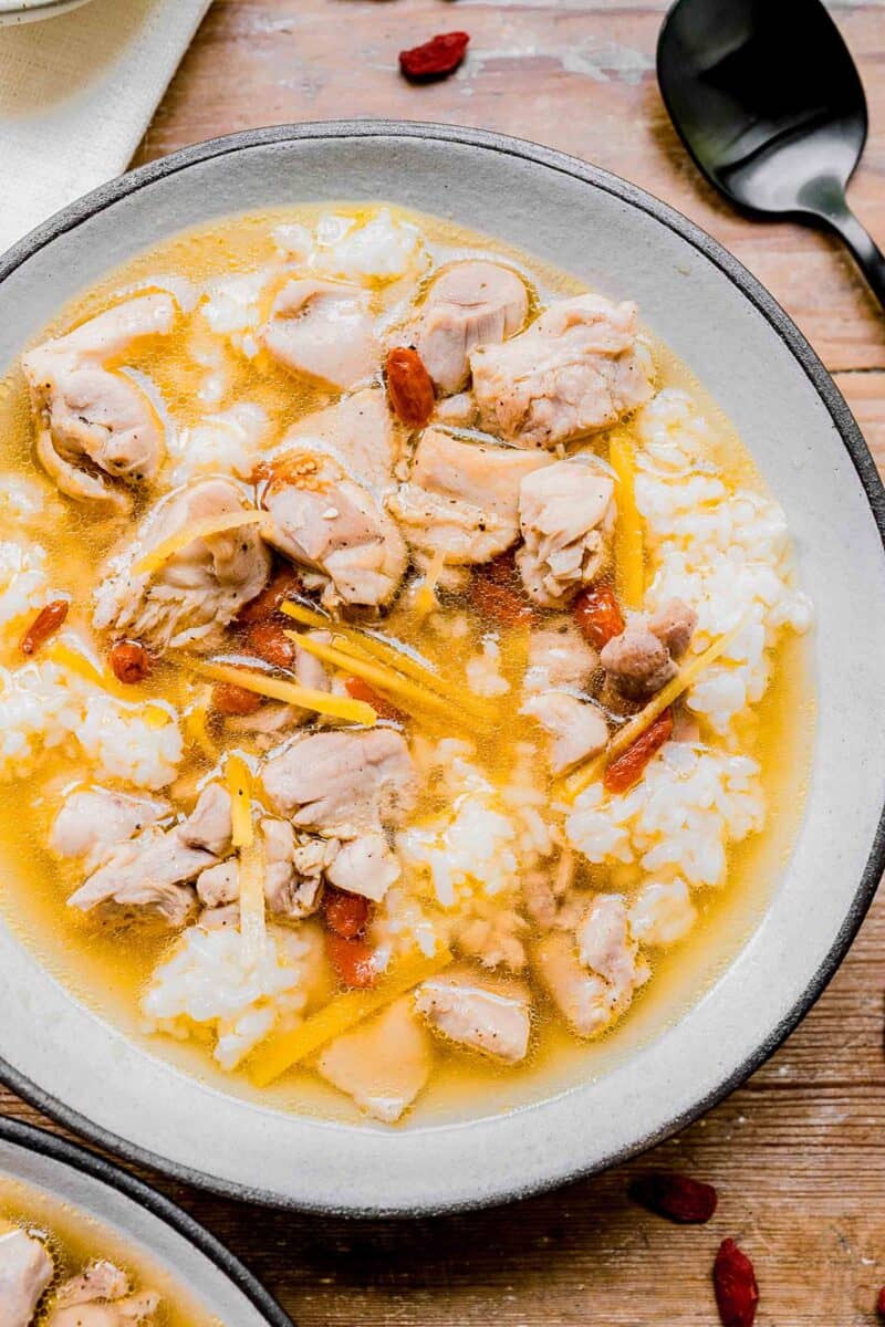 a bowl of chinese chicken soup with rice in a white bowl