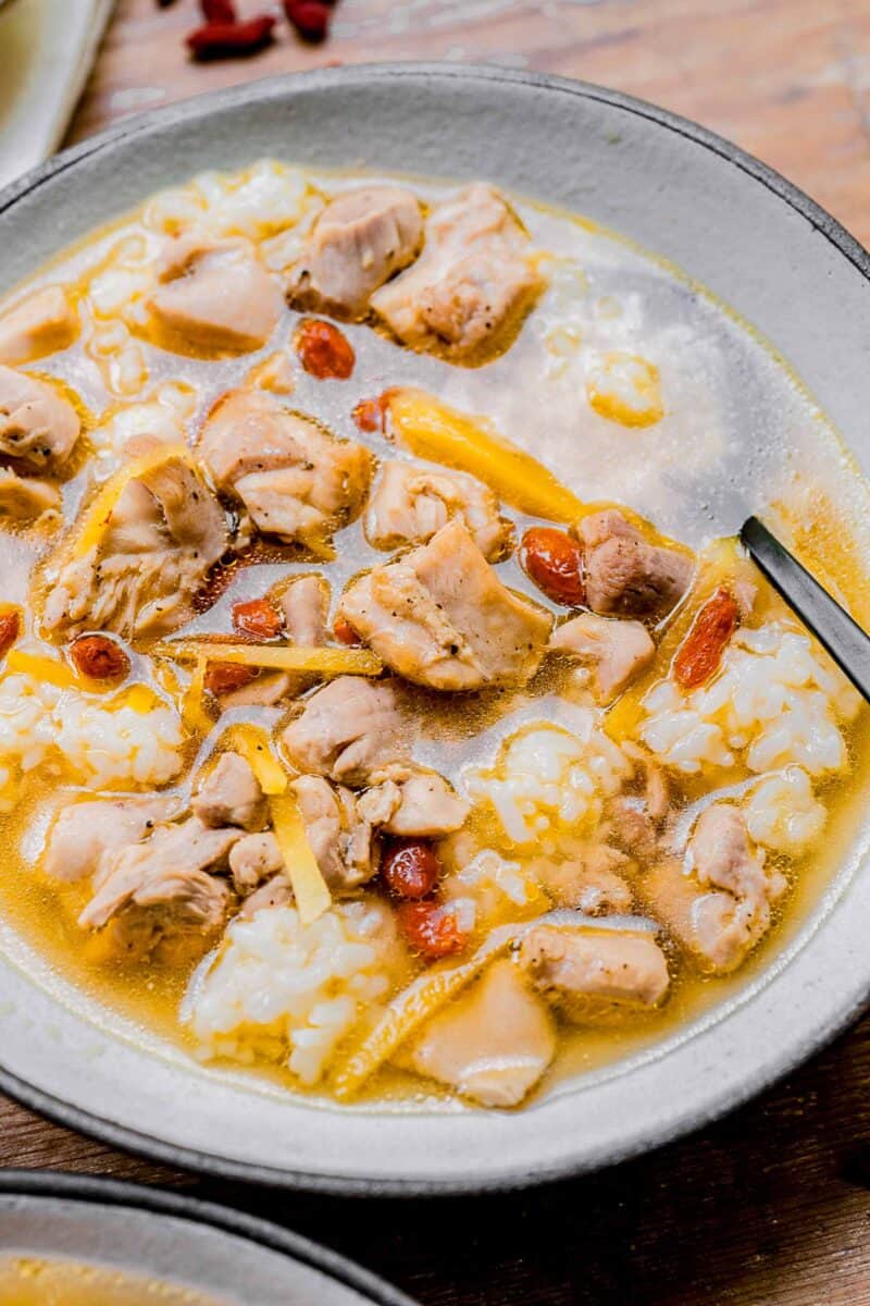 drunken chinese chicken soup in a white bowl with a spoon resting in it