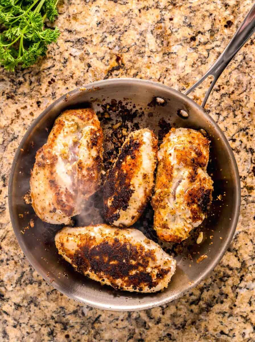 seared and browned chicken breasts in a stainless steel skillet