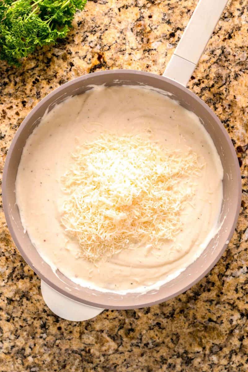 garlic parmesan cream sauce mixture with parmesan cheese on top in a nonstick skillet