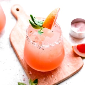 a garnished paloma is placed by itself on a board