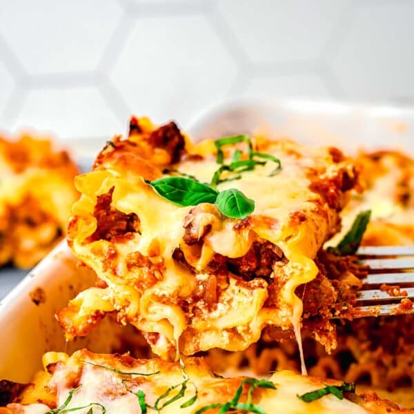 A spatula taking a lasagna roll up out of a baking pan.