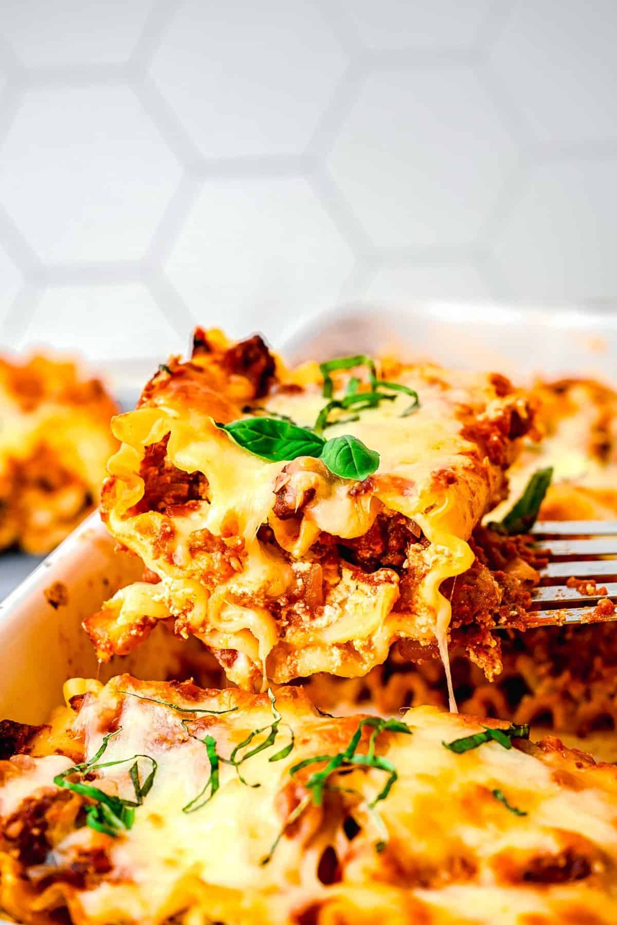 A spatula taking a lasagna roll up out of a baking pan.