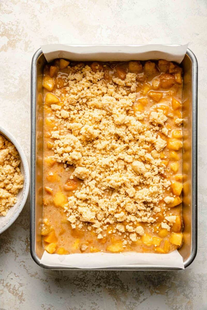 crumbled dough is placed on top of peach filling