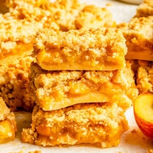 a stack of three peach crumble bars is placed on a white surface