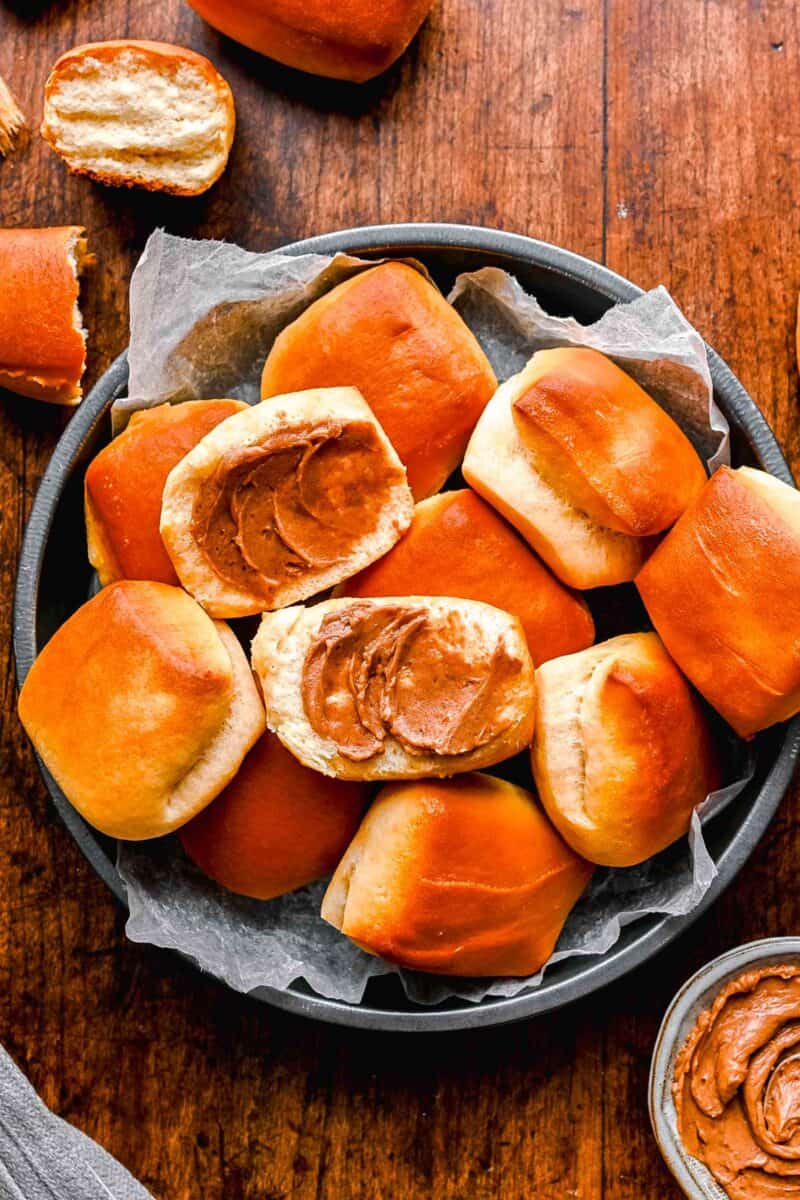 two halved, buttered rolls are placed in a container with more rolls