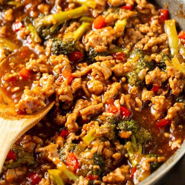 ground turkey teriyaki mixture in a grey skillet with a wooden spoon