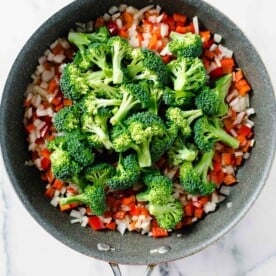 broccoli florets added on top of the cooked diced onions and red bell peppers