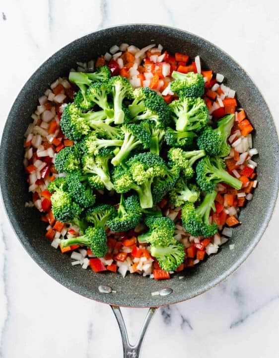 broccoli florets added on top of the cooked diced onions and red bell peppers