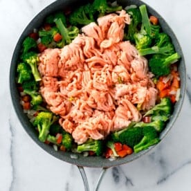 ground turkey added on top of the cooked broccoli and other vegetables in the skillet